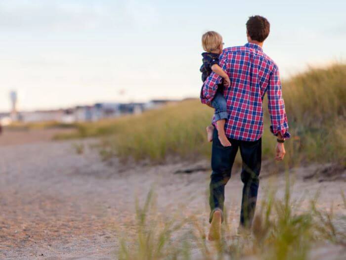 Dad carrying son on the beach alone