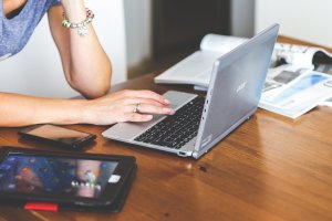 Student sitting at wooden table looks up therapy options wtih Brave Minds Psychological Services.We offer online therapy for college students, online therapy for teens in new jersey, and more! Contact us today!