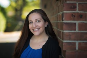Lauren smiles at the camera in front of a brick wall. She is a therapist offering couples therapy in Scotch Plains, NJ. Contact her to learn more about marriage counseling in Westfield, NJ and other services! 07076