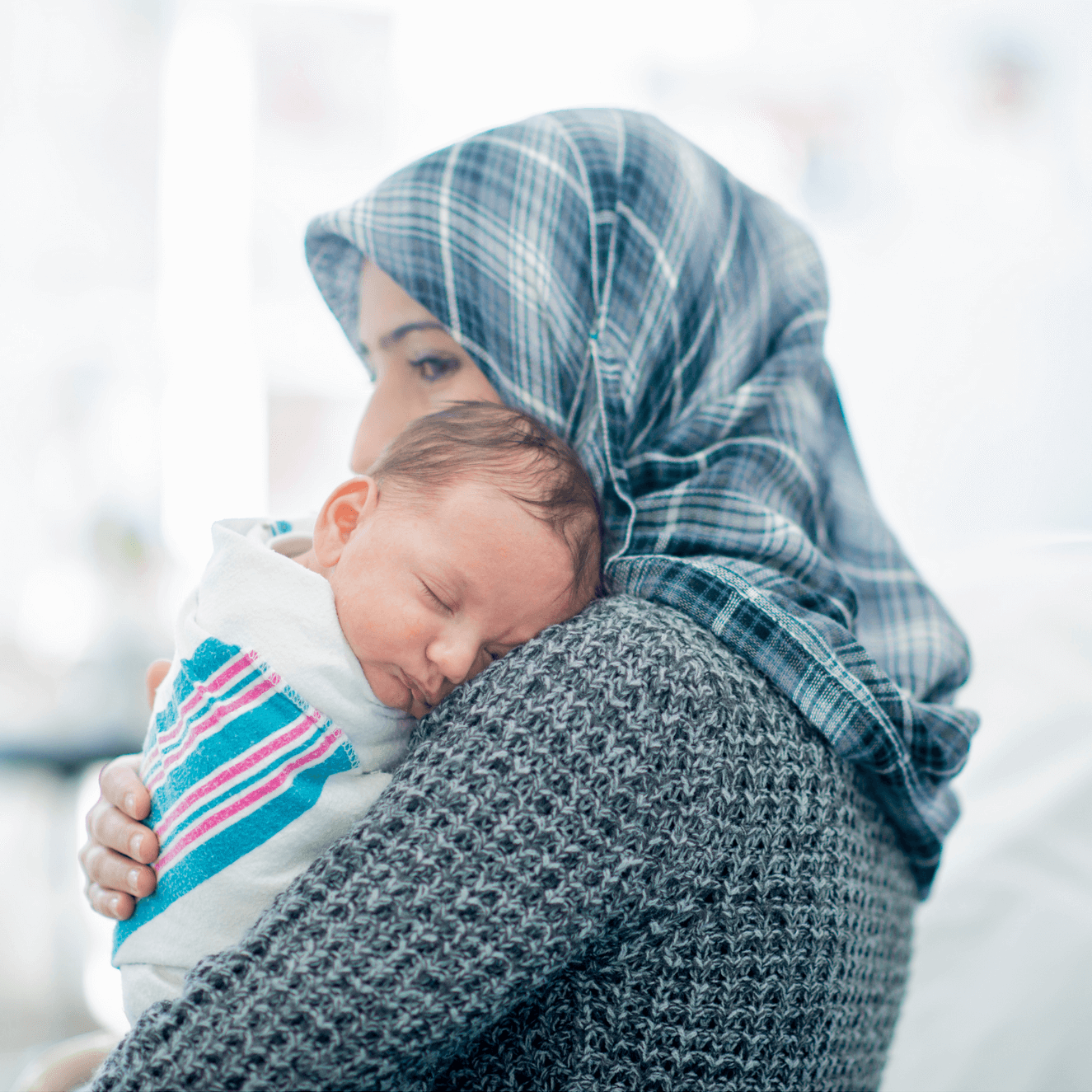woman with a head covering holding an infant