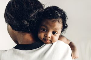 Mother with her baby over shoulder, baby is smiling and happy because mom is happy. Empowered mothers are happy mothers and therapy for postpartum and birth trauma therapy can help you! Online in New Jersey and Birth Trauma therapy in Scotch Plains, NJ can help you today.