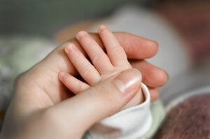 Baby holding parent's hand close up. Feelings of PTSD after a traumatic birth is common. Birth Trauma therapy in Scotch Plains, NJ can help you heal and feel more hopeful about your baby's life. Postpartum therapists at Brave Minds Psychological Services can help folks in Scotch Plains, Fanwood, Cranford or Westfield. Also, in online therapy in New Jersey.