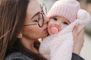 Mother holding her new baby wrapped in a pink blanket after attending postpartum anxiety counseling. In Scotch Plains, NJ you too can get help at Brave Minds Psychological Services. Postpartum depression is available for Fanwood, Westfield, and Cranford residents.
