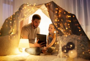 Happy father and daughter doing online therapy in new jersey on a laptop. Telehealth in New Jersey doesn't have to be difficult to access for parents and children with a child therapist in Westfield, NJ from Brave Minds psychological services.