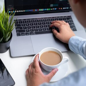 Close up of the hands of a student in collared shirt typing on their laptop, with a cup of coffee in their left hand. Brave Minds Psychological Services offers online therapy for college students in new jersey, anxiety scotch plains, nj, and more! Contact us today! 