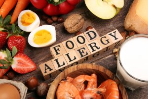 Allergy food as almonds, milk, cheese, strawberry, seeds, eggs, peanuts and crustaceans or shrimps with wooden letter food allergy. If you're wondering can food allergies cause panic attacks, you can get therapy for food allergies and anxiety attacks in New Jersey at Brave Minds Psychological Services.