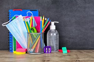 School supplies and COVID 19 prevention items on a desk against a chalkboard background. Back to school during pandemic concept for virtual learning during COVID. You can get anxiety treatment in Westfield, NJ and Anxiety treatment in Cranford, NJ with Brave Minds in Scotch Plains, NJ