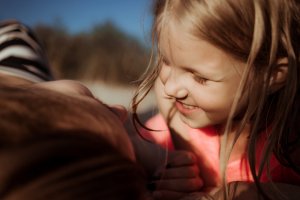 daughter smiles at mom while laying on the beach. Get support as a single parent in Scotch Planes, NJ and parent counseling at brave minds psychological services 