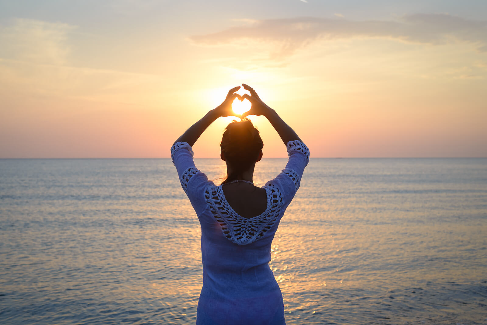 Woman Makes Heart With Hands On Beach. Symbolizing the love languages for children and teens with anxiety for child therapy and teen therapy in Scotch Plains, NJ. You can get help with parent coaching and therapy for children with anxiety here and via online therapy in New Jersey