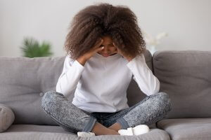 teen girl sits with her head in her hands on the floor after experiencing trauma and PTSD. She gets emdr for teens in Scotch Planes, NJ with an EMDR therapist 