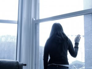 A monochromatic image of a woman in black looking out a window. This could represent the cold pain of trauma from the past. We offer EMDR therapy in Scotch Plains, NJ. Contact an EMDR therapist to learn about the benefits of EMDR for children.