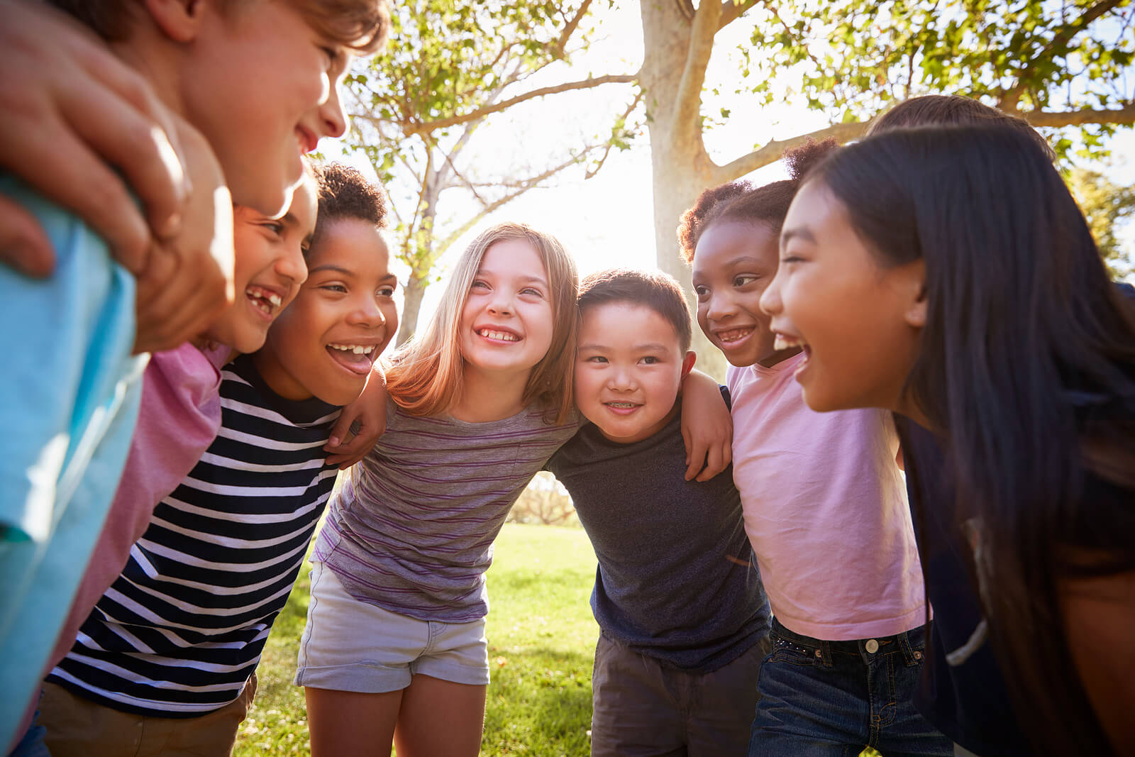 A group of kids huddle in a circle as they smile at one another. Contact a child therapist in Scotch Plains, NJ for support with child therapy for anxiety, EMDR therapy for children, and more!