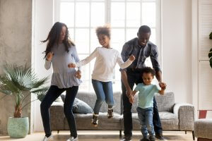 A happy family smile as they dance with one another in the living room. This could represent the joy a child therapist in Scotch Plains, NJ can help your family cultivate. Learn about child therapy for anxiety, EMDR therapy for children and other services.