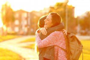 A teen smiles as she hugs her friend on a sunny evening. This happiness could represent how counseling for teens in Scotch Plains, NJ can benefit relationships. Learn more about online therapy for teens by searching "teenage anxiety therapist near me." 