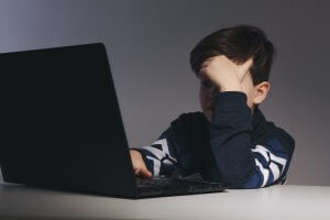preteen boy looks at something upsetting on the computer. If you're a parent freaking out about your child's actions, please contact a child therapist for parenting counseling in Scotch Planes NJ at Brave Minds Psychological Services