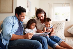 A family smiles together as they read a book. This could represent the peace that anxiety counseling in Scotch Plains, NJ can provide with child therapy for anxiety. Contact us to learn more about anxiety treatment, or search "teenage anxiety therapist near me" today. 