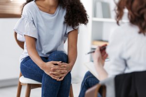 A woman listens as a therapist holding a clipboard gestures with her hand. This could represent therapy for perfectionism in Scotch Plains, NJ. Contact a perfectionism therapist to learn more about anxiety counseling in Scotch Plains, NJ and other services. 