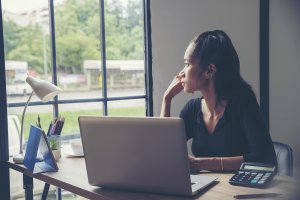 A woman sits at a computer desk as she watches the world outside her window. A perfectionism therapist in Scotch Plains, NJ can help you overcome obsessive thoughts. Learn more about anxiety counseling in Scotch Plains, NJ today.