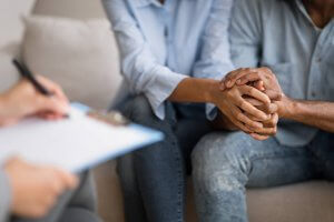 A couple hold hands while a therapist writes on their clipboard. This represents couples therapy in Scotch Plains, NJ. Learn more about marriage counseling in Westfield, NJ today. 07076