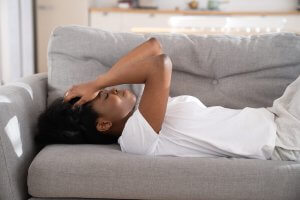 A woman lays on a sofa with hands resting against her forehead. Sexual violence prevention in Scotch Plains, NJ can help prevent aganist rape culture. Learn how online therapy for sexual assault in New Jersey can help you today! 07076