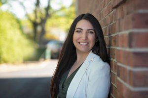 Jessca smiles while standing against a brick wall. Learn how an EMDR therapist in Scotch Plains, NJ can offer support with overcoming past trauma. Search for emdr therapy near me or EMDR therapy in Scotch Plain, NJ