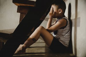 Image of a sad child holding his head while hiding. Narcissistic abuse can affect people of all ages. That is why we offer EMDR therapy for kids in Scotch Plains, NJ 07076.