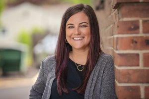 Casey smiles while leaning against a brick wall. Learn how an EMDR therapist in Scoth Plains, NJ can offer support via emdr therapy in New Jersey today. Search for EMDR therapy near me and other services for support. 