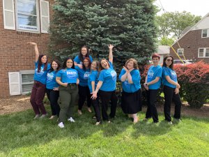 A group of therapists from Brave Minds. They are standing outside in matching blue t-shirts that say Brave Healers. They are standing in silly poses and having fun.