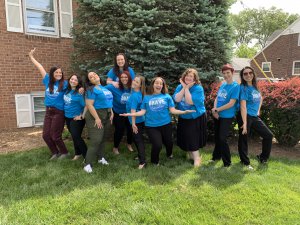 A group of therapists from Brave Minds. They are standing outside in matching blue t-shirts that say Brave Healers. They are standing in silly poses and having fun.