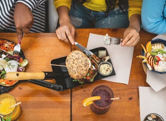 A top-down view of friends eating a variety of foods at a table. Learn how to overcome food allergies and anxiety by searching for anxiety treatment today. Search “signs of anxiety somerville, nj or westfield, nj” for support.