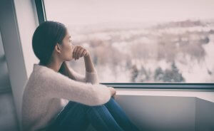 Image of a woman looking out the window showing the effects of food allergy and anxiety and anaphylactic reaction. Working with a trauma therapist in Scotch Plains, NJ can help reduce that fear.