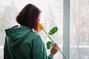 A teen smells a flower while looking out a window. Learn more about counseling for teens in Scotch Plains, NJ by getting in touch with a teen counselor Scotch Plains, NJ today.