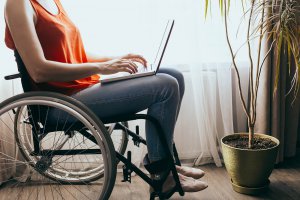 A person in a wheelchair types on a laptop next to a window. Learn more about how online therapy in New Jersey can offer support by searching “online therapist new jersey” or Westfield NJ counseling today.