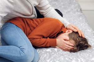 Shows a child covering their face and being comforted by their parent. Symbolizes how selective mutism in scotch plains nj needs early treatment to help ease anxiety and help with social skills.