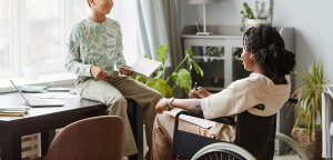 Shows a child talking with their mom who is in a wheelchair. Represents how a selective mutism therapist will help your child learn coping skills to manage their anxiety.