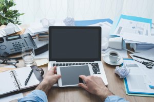 A close-up of a cluttered workspace with a laptop and work files. Learn more about how online therapy in Scotch Plains or Branchburg New Jersey areas can offer support by searching “online therapist new jersey” or Westfield NJ or Somerville NJ counseling today.