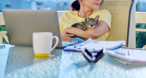 A person holds a cat in their arms while looking around their workspace. Learn more about online therapy in New Jersey and the support Scotch Plains and Branchburg counseling can offer. Search “online therapist new jersey” to learn more today.