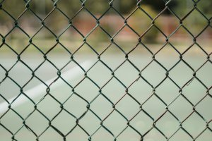 a fence with a blurry background at a high school with teens and adolescents who may be experiencing bullying or a failed system, looking for a teen therapist that can help with stress, anxiety, depression, trauma, and more in the Scotch Plains NJ and Branchburg NJ areas.