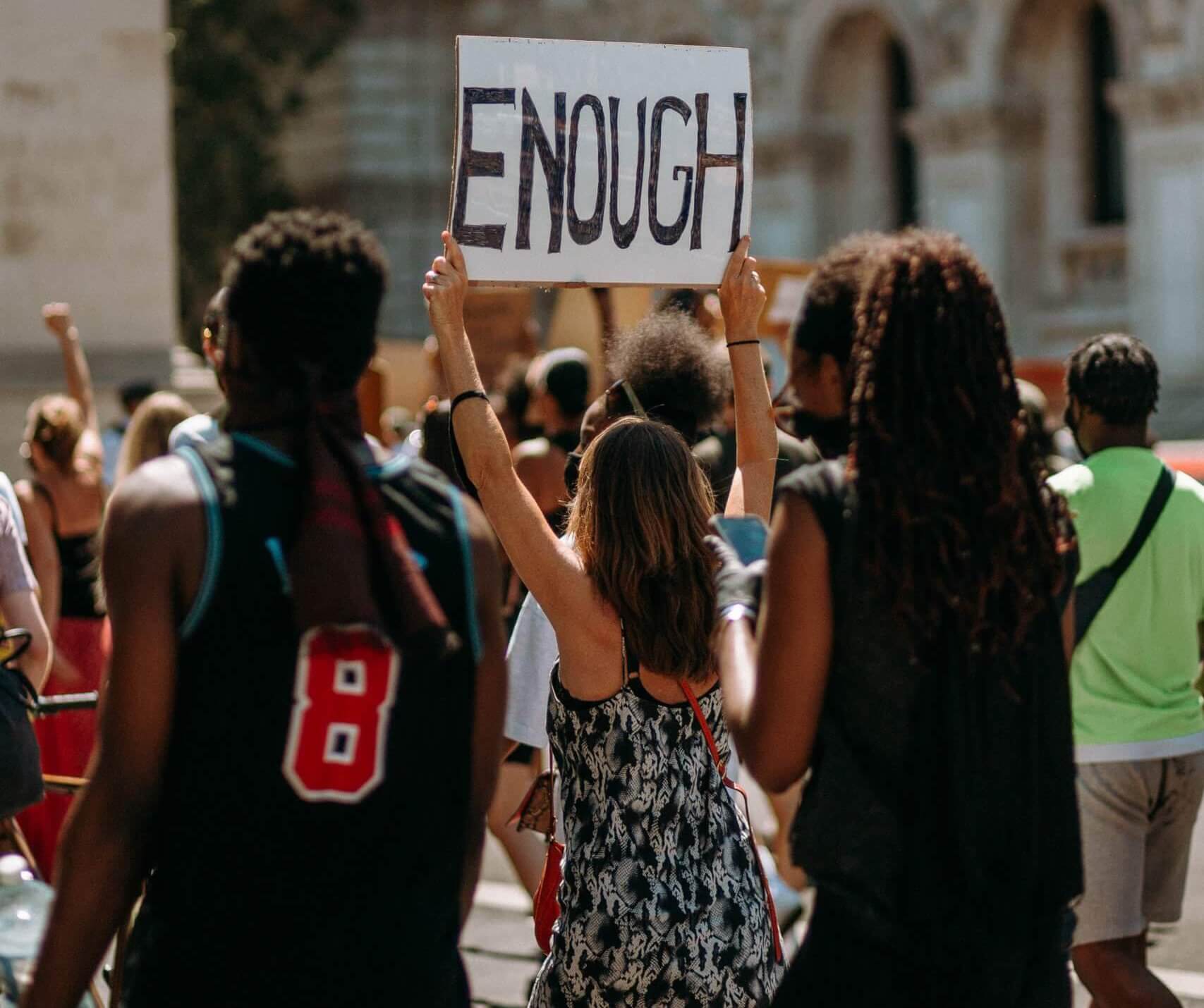 a group of protestors, one holding up a sign that reads, "Enough", protesting a high school with bullying and a system that has failed to keep it's students safe. Teens are looking for mental health help and teen therapy in Somerville, NJ and Fanwood, NJ and surrounding areas