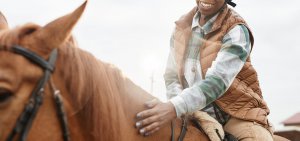 Shows an individual riding a horse while also petting it. Represents how counseling for teens in scotch plains, nj strives to also support equestrians with their struggles.