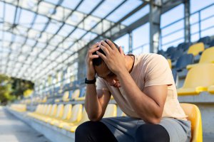 A college student hangs their head while sitting in a stadium alone. Learn how counseling for teens in Scotch Plains, NJ can offer support with overcomng burnout and isolation. Learn more about online therapy for teens and online therapy for college students in New Jersey.