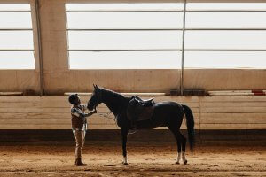 A horse rider stands in front of their horse while holding their reigns. This could represent the support equestrian related trauma therapy in Scotch Plains, NJ can offer with overcoming equestrian related stress. Contact a trauma therapist in Scotch Plains, NJ to learn more today.