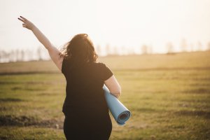 A person holds up their hand in a peace sign while holding a yoga mat. Learn more about the support a trauma therapist in Scotch Plains, Nj can offer by searching for online therapy in New Jersey. 