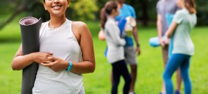 A person smiles while holding a yoga mat near her friends in the park. Learn how trauma therapy in Scotch Plains, NJ can help you achieve the life you want to live. Learn more by contacting a trauma therapist in Scotch Plains, NJ today.