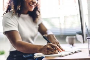 Image of a teen girl writing in a notebook which can help with anxiety in teens. Representing one of the techniques a therapist for teens might suggest in therapy in Branchburg, NJ.