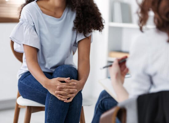 A woman sits across from a woman holding a clipboard. This could represent the benefits of meeting with a trauma theapist in Scotch Plains, NJ. Learn more about Scotch Plains therapy by searching for "therapist Branchburg, NJ" today.