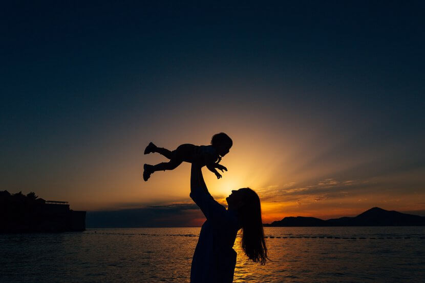 A mother holds their baby above their head against the light of the rising sun. Learn how a child therapist in Branchburg, NJ can offer help for new parents. Search for “single parent scotch plains, nj” to learn more about parenting help today.