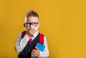 Image of a boy with school supplies and a mask stands alone. This could represent the ioslation that child therapy for anxiety can help address. A child therapist in Scotch Plains, NJ could help him by addressing his selective mutism.
