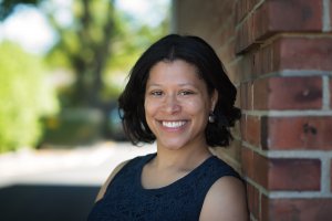 Fawn smiles at the camera while posing against a brick wall. She is a trauma therapist in Scotch Plains, NJ. Search for trauma therapy near me for support via trauma therapy in Scotch Plains, NJ. 