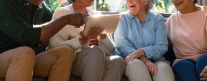 Four older smiling individuals look at a tablet while sitting together. This could represent an understanding of family that a couples counselor in branchburg, nj can help you achieve. Learn more about the benefits of Scotch Plains therapy by searching for therapist branchburg, nj.